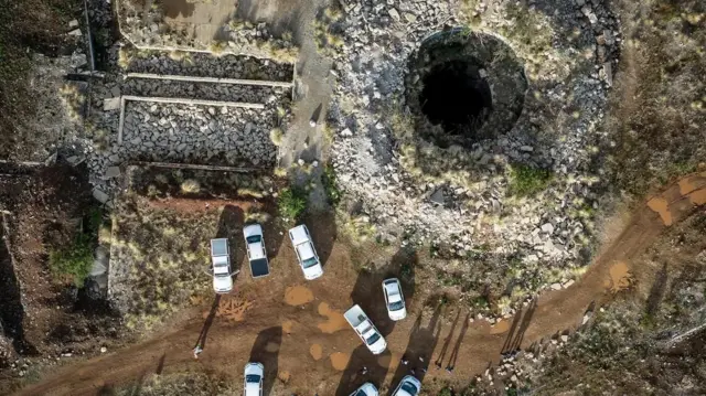 One aerial view of di mineshaft wit some vehicles wey dey parked nearby