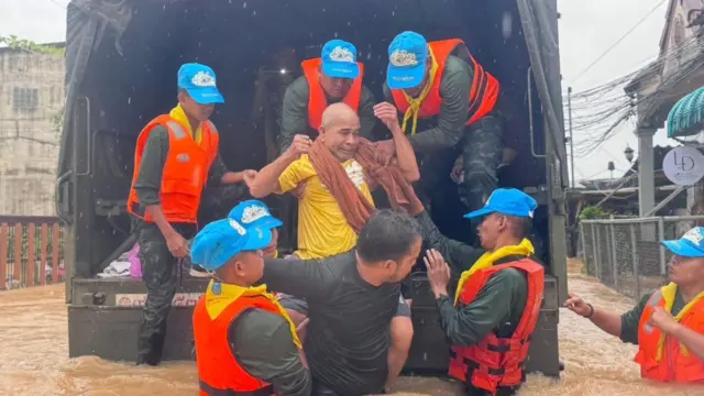 ထိုင်းနိုင်ငံ၊ ဟတ်ယိုင်မြို့မှာ ရေနစ်မြုပ်တဲ့ နေအိမ်က ဒေသခံတစ်ဦးကို ကူညီကယ်ဆယ်ပေးနေတဲ့မြင်ကွင်း