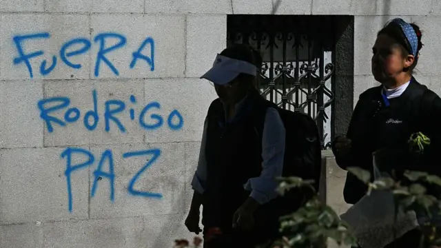 Mujeres pasan junto a un grafiti que dice "Rodrigo Paz fuera", en referencia al presidente de Bolivia, en La Paz, el 19 de mayo de 2026.