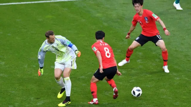 Manuel Neuer pierde la pelota en el medio campo contra dos jugadores de Corea del Sur.