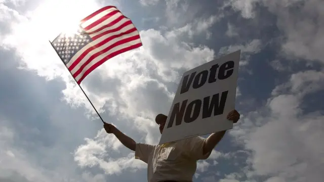 Bandera de Estados Unidos y cartel de "vote now".