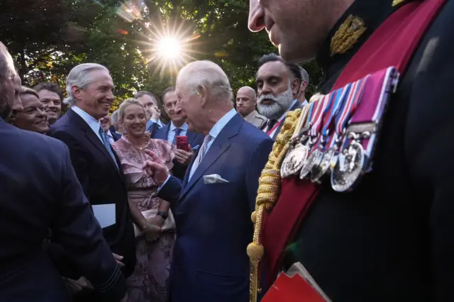 در بالای تصویر، زمانی که خورشید از میان درختان باغ کاخ سفید بیرون می‌زند و پادشاه با مردم در مهمانی باغ ملاقات می‌کند، و نشان‌های نظامی بر تن یکی از مهمانان در پیش‌زمینه دیده می‌شود، درخشش لنز دیده می‌شود.
