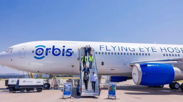 Plane wey dem write flying eye hospital dey di picture wit pipo wey dey come down from am. 