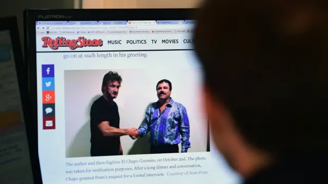 Un hombre mira un monitor con Sean Penn y Joaquín Guzmán en una foto