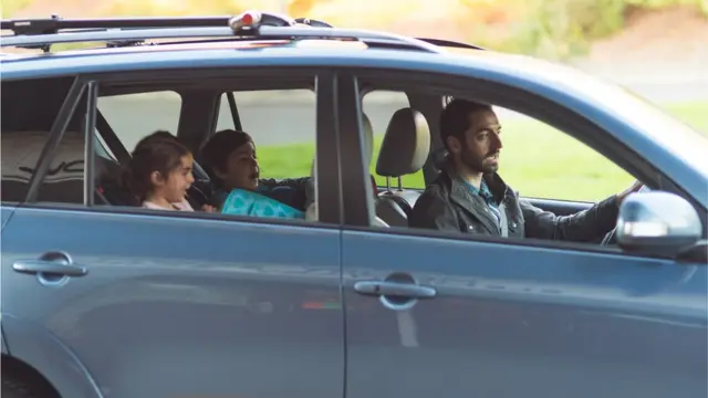 Un padre en un auto con dos niños