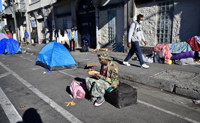 Barracas e pessoas vivendo na rua, durante o dia