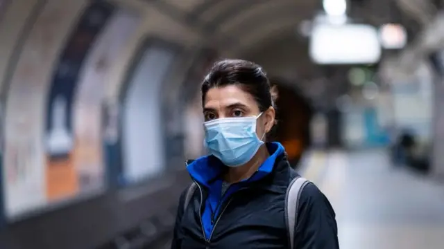 마스크를 쓴 여성이 지하철 승강장에 서 있다