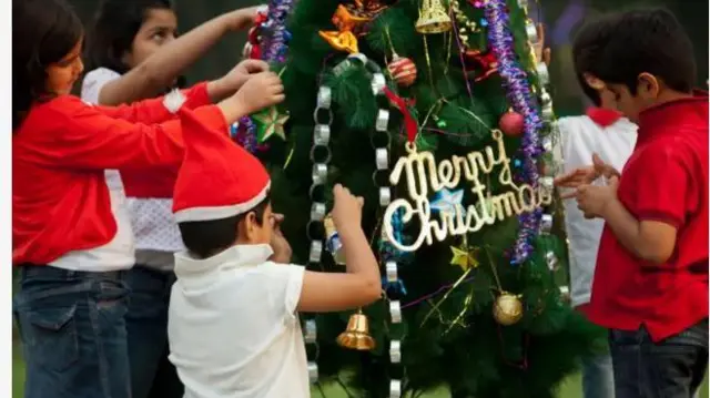 Aworan awọn ọmọ India nigba ti wọn n to nnkan alarambara mọ ara igi Keresimesi.