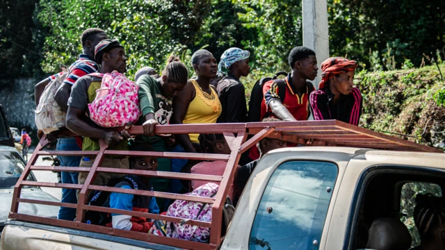 Pessoas carregam mochilas e bolsas com seus pertences enquanto fogem da violência no distrito Kenskof, em Porto Príncipe (Haiti), na parte de trás de uma pick-up, no dia 29 de janeiro de 2025