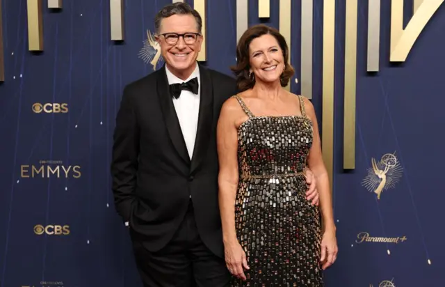 Voditelj emisije „The Late Show“ Stiven Kolbert u crnom odelu sa suprugom Evelin Mekgi-Kolbert u svetlucavo sivoj haljini