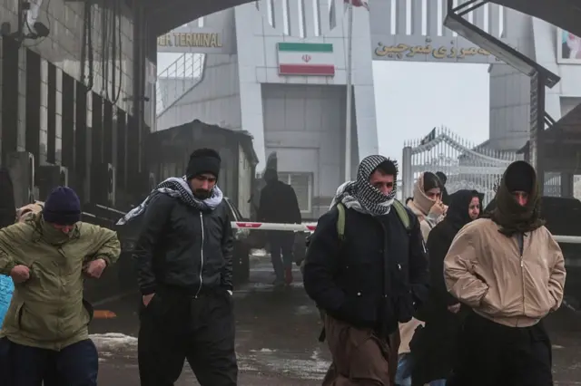 Иранские курды прибывают на пограничный переход Хаджи Омран с Ираном (на заднем плане виден иранский флаг) в автономном северном курдском регионе Ирака 1 февраля 2026 года. Переход открыт для путешественников и экономической торговли