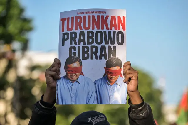 Mahasiswa memegang plakat yang menyerukan pengunduran diri Presiden Indonesia Prabowo Subianto dan Wakil Presiden Gibran Rakabuming Raka, selama protes terhadap kenaikan harga bahan bakar yang tidak disubsidi, pengeluaran pemerintah yang tidak efisien, keterlibatan militer dalam urusan sipil, dan program makan sekolah gratis pemerintah, di Surabaya pada 22 Juni 2026.