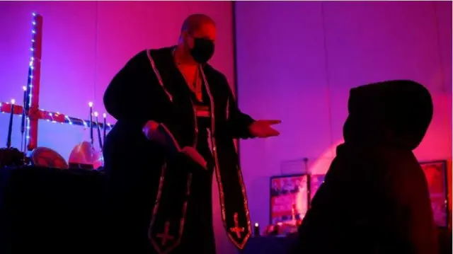 Pendeta Rose d'Arc melakukan upacara unbaptism untuk seorang hadirin di Little Black Chapel