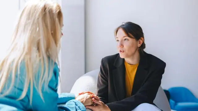 دو زن در حال نشستن روی صندلی‌های راحتی و گفتگو کردن. مربی، روان‌درمانگر، روانشناس یا مشاور زن و مراجع یا مشتری.