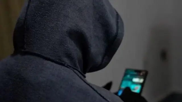 ጀርባውን ሰጥቶ ስልክ የሚነካካ ግለሰብ