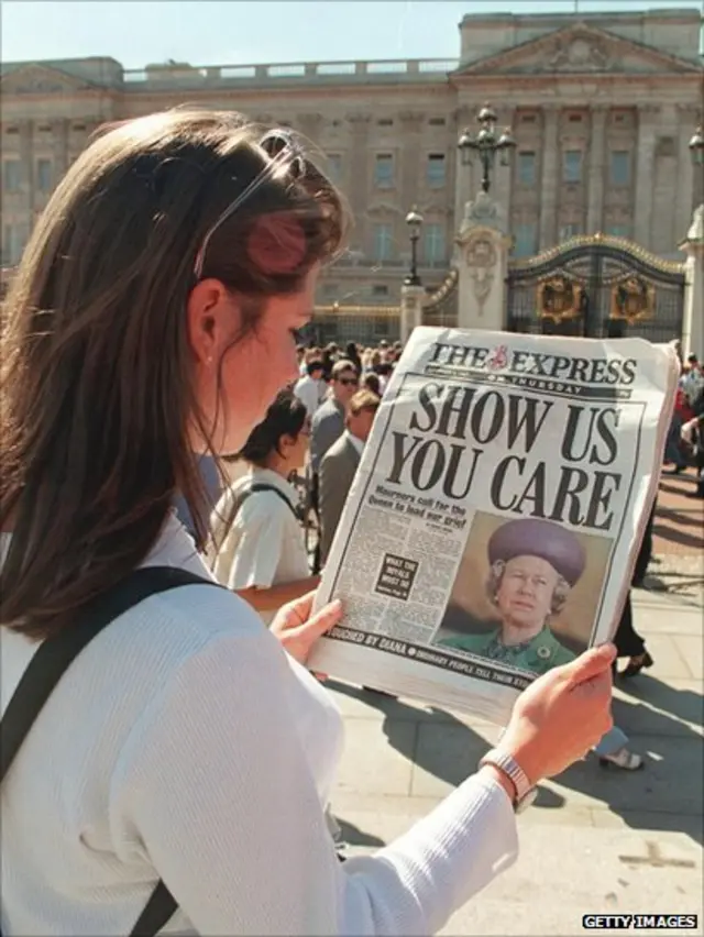 Qız Buckingham sarayının qarşısında qəzet oxuyur