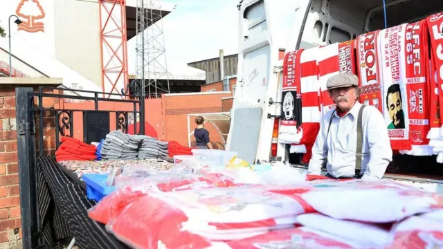 بائع يبيع أوشحة وبوسترات تحمل صورا لمشاهير اللاعبين