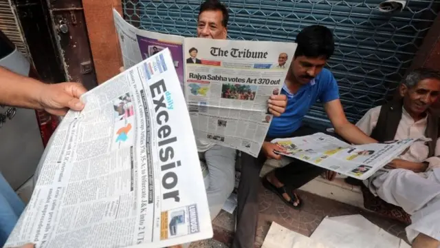 कश्मीर की ख़बर पढ़ते लोग