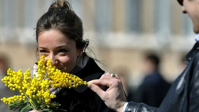 मिमोसा का फूल लेती हुई एक महिला