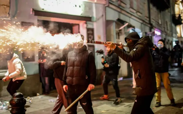 Демонстрант в маске выставил перед собой зажженный файер