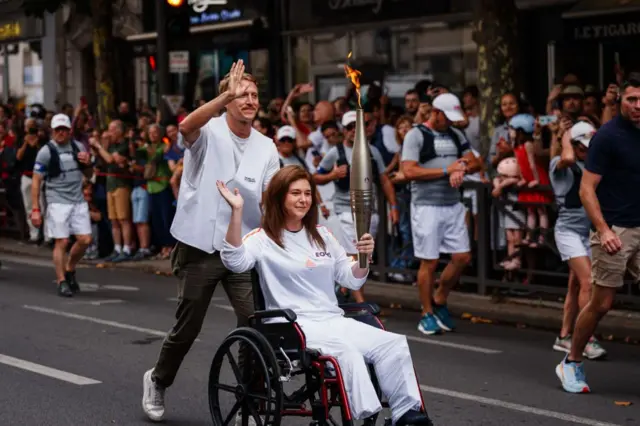 كريستينا عاصي وديلان كولنز من وكالة الصحافة الفرنسية يحملات الشعلة الأولمبية الأحد في ضاحية باريس تكريماً للصحافيين الذين سقطوا خلال أداء الواجب