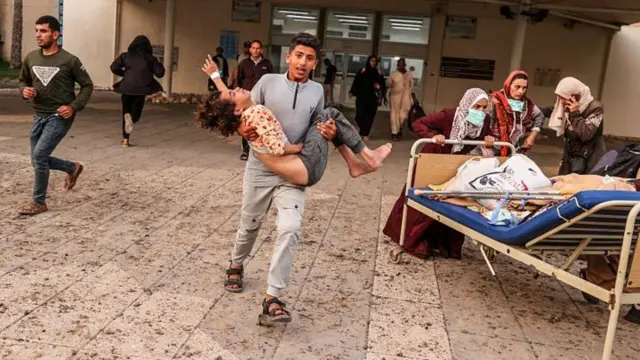 أشخاص يركضون خارج أحد مستشفيات غزة.