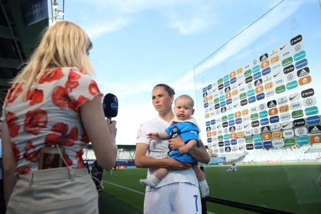 Sara Björk Gunnarsdóttir tient son bébé tout en parlant à un journaliste sur le terrain.