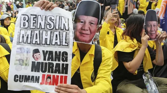 Seorang demonstran mengenakan masker bergambar wajah Presiden Indonesia Prabowo Subianto dalam aksi protes anti-pemerintah di Jakarta, Jumat (12/06).