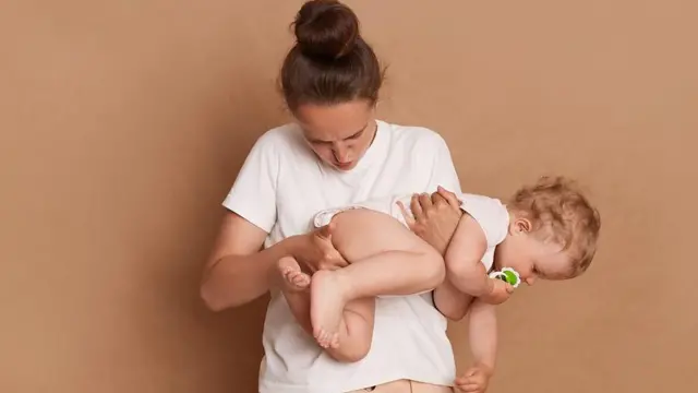 बच्चे का डायपर चेक करती महिला