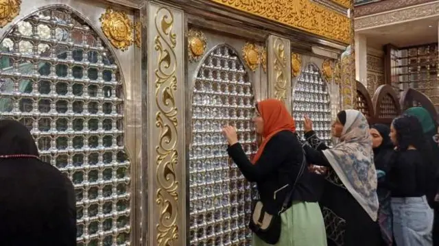 কায়রোর হুসাইনি মসজিদের ভেতরে কয়েকজন নারী হাত দিয়ে লোহার তৈরি প্রাচীর ধরে আছেন