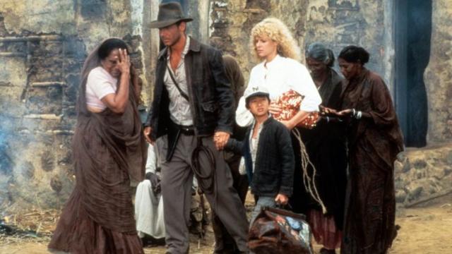 Harrison Ford e Ke Huy Quan caminhando de mãos dadas em filme de 1984