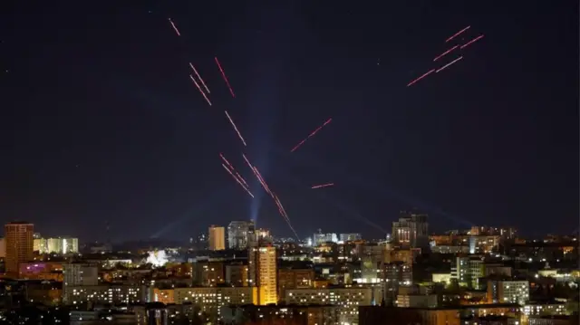 Нічний Київ і сліди від прожекторів і роботи ППО в небі під час російської атаки