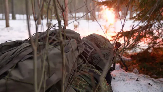 Um soldado na neve, com chamas ao fundo