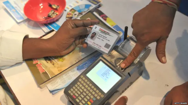 n Indian visitor gives a thumb impression to withdraw money from his bank account with his Aadhaar or Unique Identification