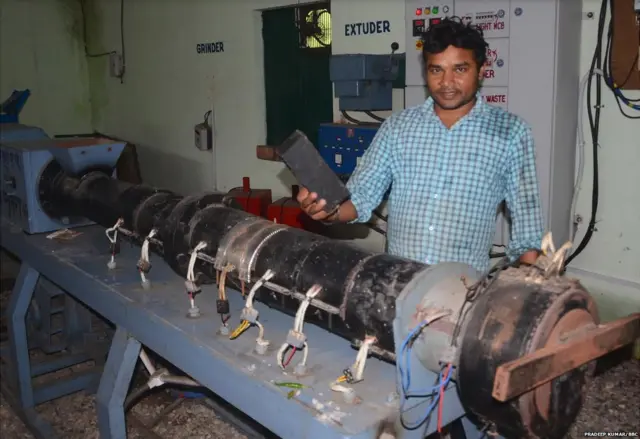 प्लास्टिक से बनी ईंट दिखाता शख़्स