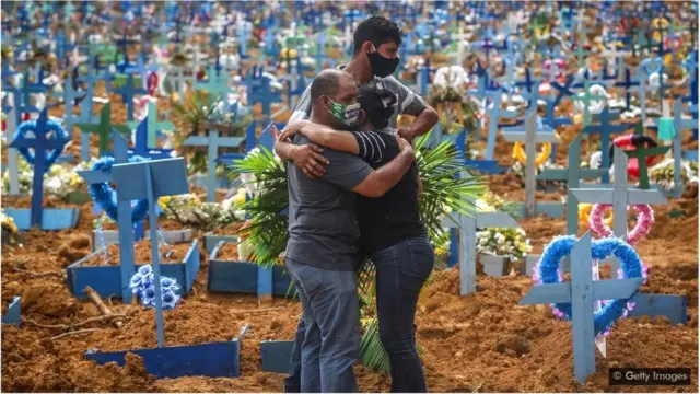 क़ब्रिस्तान में गले मिलते लोग