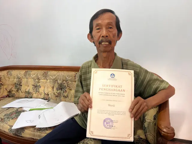 Werdi memegang sertifikat penghargaan pemugaran 1973-1983.