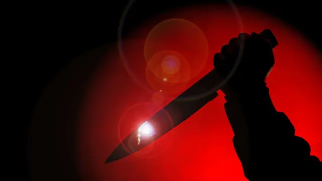 Una mano con un cuchillo en fondo rojo
