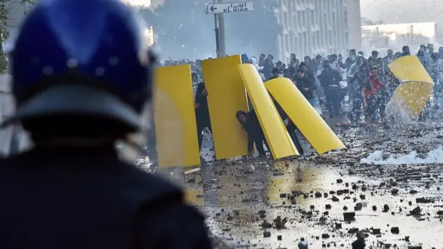 Protestocular 1 Mart"taki gösterilerde polis müdahalesinden korunmak için barikat oluşturuyor