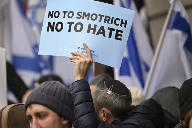  أشخاص يحملون لافتات وأعلام إسرائيلية يتجمعون للاحتجاج على وزير المالية الإسرائيلي بتسلئيل سموتريتش خارج فندق غراند هياة حيث يحضر مؤتمرا وسط مقاطعة رسمية بعد تعليقاته على القضاء على قرية حوارة الفلسطينية، في 12 مارس/آذار، في واشنطن العاصمة، الولايات المتحدة