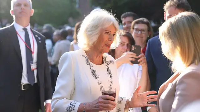 Queen Camilla chats with a guest at the garden party
