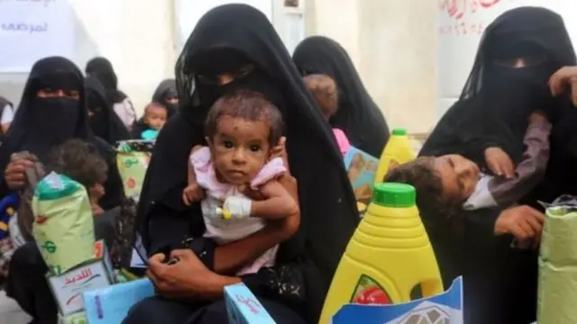 نساء يحملن أطفالهن في اليمن
