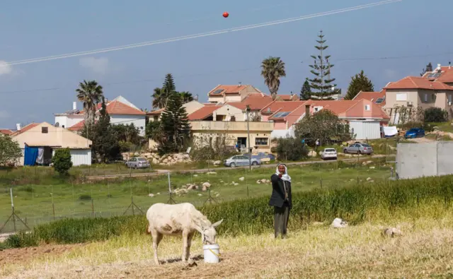 Batı Şeria'da bir Filistinli, arka planda Yahudi yerleşimleri görülüyor.