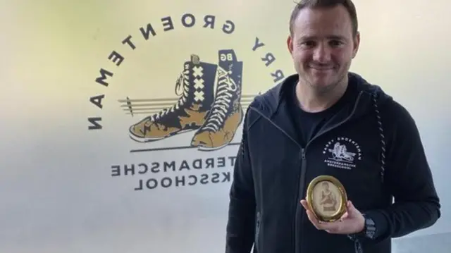 گرونتمن با پرتره قاب شده بن بریل، در باشگاه بوکس خود در آمستردام 