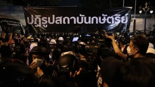 ผู้ชุมนุมกลุ่ม "ราษฎร" ถือป้ายเรียกร้องปฏิรูปสถาบันกษัตริย์ หลังจากเดินขบวนจากสามย่านมาถึงสถานทูตเยอรมนีเมื่อวันที่ 26 ต.ค. 2563