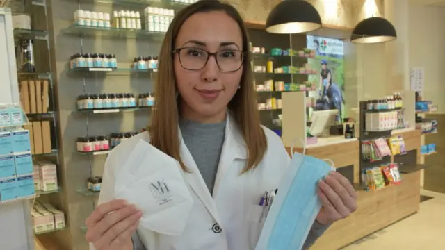 Una boticaria en Austria sostiene una FFP2 en su mano derecha y otra mascarilla de algodón en su mano izquierda