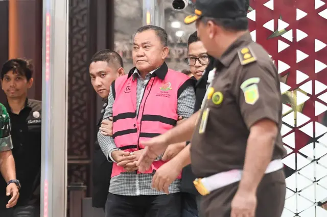 Mantan Wakil Kepala Badan Gizi Nasional, Lodewyk Pusung (tengah), berjalan memasuki mobil tahanan di Kejaksaan Agung, Jakarta, Rabu (03/06).