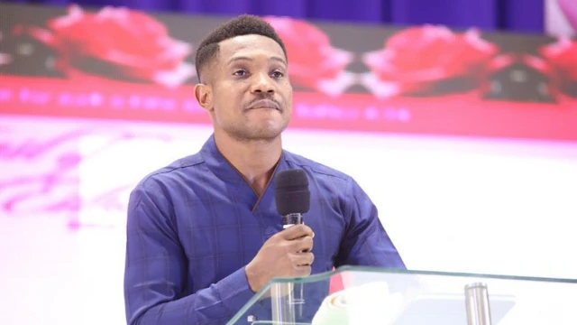 Pasitọ Jerry Eze mu gbohun-gbohun lọwọ, o si wọ aṣọ olomi aro