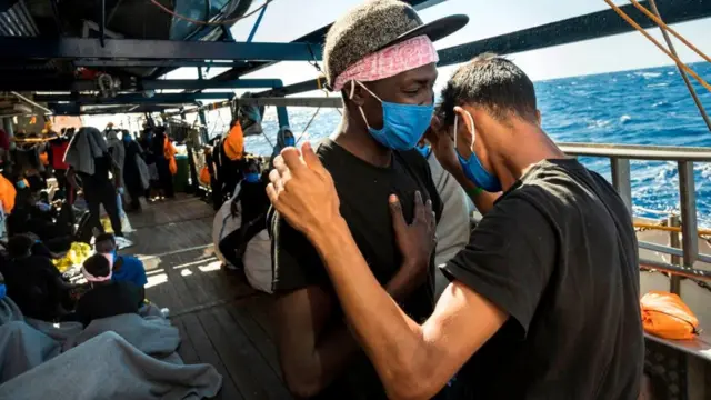 A Libyan migrant (R) and an east African migrant pray a Muslim prayer for reconciliation onboard the Sea-Watch 4 civil sea rescue ship on September 01, 2020, on sea off the coast of Sicily, Italy,