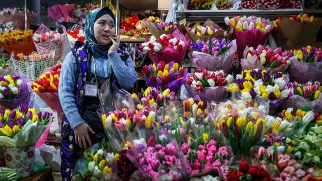 Mulher com véu vendendo flores